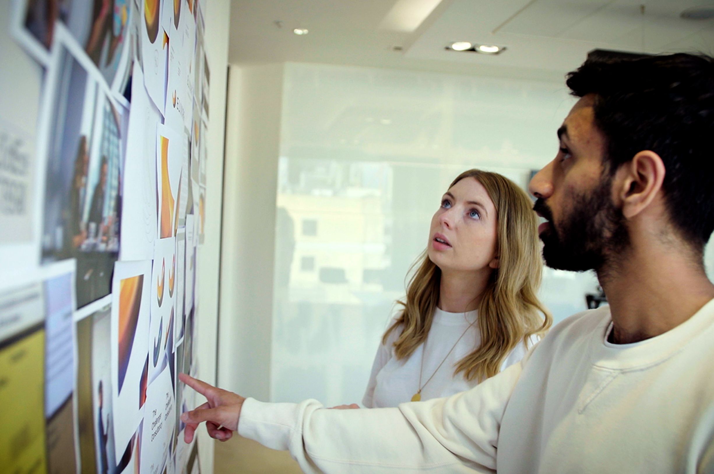 A man and a woman looking at a wall full of branding assets.