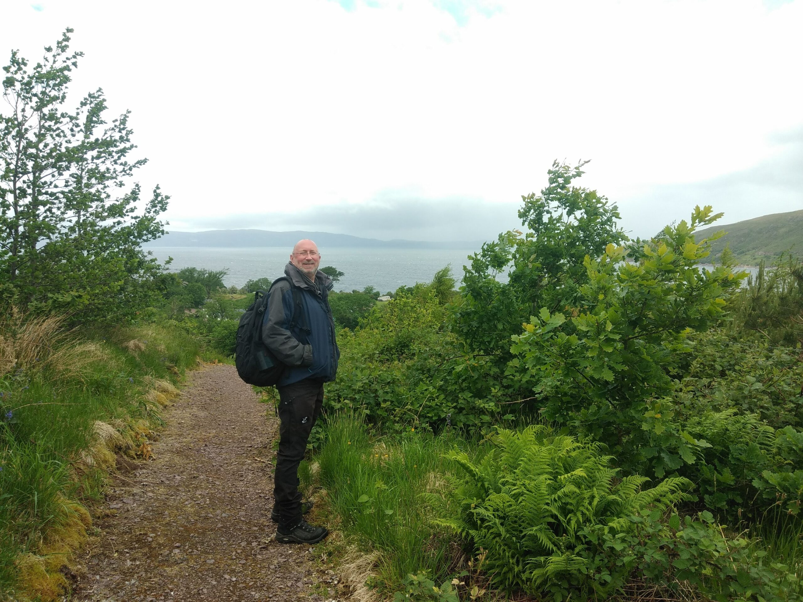 Man standing in the middle of greenery on a hike.